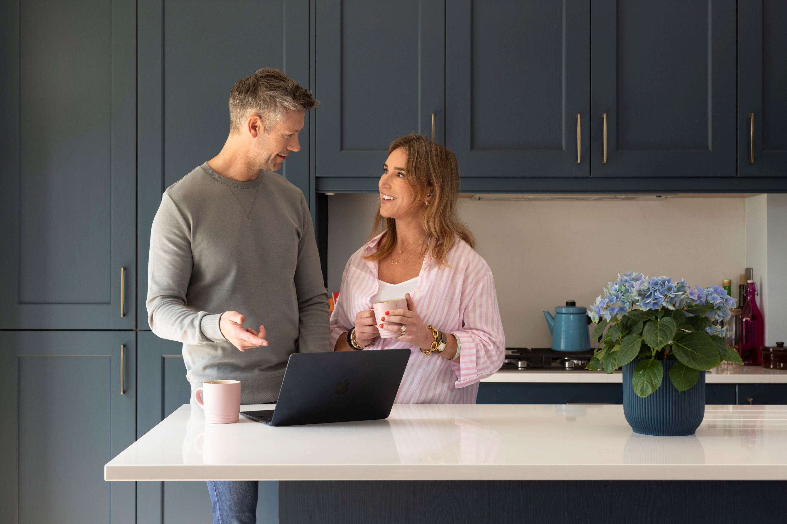 WOman and man looking at each other in a kitchen with a laptop open on the island